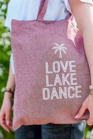Lakedance canvas tas in een donkerroze/paarse kleur. Witte print met LOVE LAKE DANCE en een palmboom.